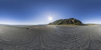 the time lapsing lens captures people on the beach and mountain ranges are visible in the sky