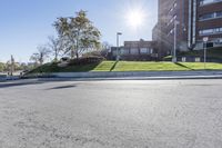 an empty road next to a large building on a sunny day on a sunny, windy day