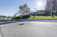 an empty road next to a large building on a sunny day on a sunny, windy day