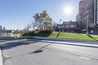 an empty road next to a large building on a sunny day on a sunny, windy day