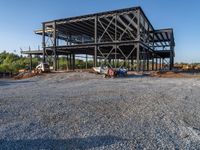 a picture of a building being built on a field near a forest in the background