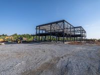 a picture of a building being built on a field near a forest in the background