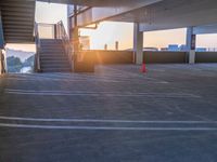 a parking lot with stairs and steps leading up to a balcony area at sunset next to some steps