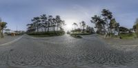 a 360 view of a street with cars and trees in the background and people walking down it