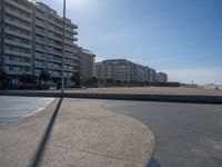the empty beach and paved walkway in front of the buildings on the beach and a bus stop