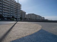 the empty beach and paved walkway in front of the buildings on the beach and a bus stop