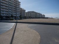 the empty beach and paved walkway in front of the buildings on the beach and a bus stop