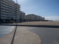 the empty beach and paved walkway in front of the buildings on the beach and a bus stop