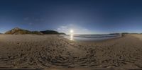 the view looking up at a beach from the sand with waves in the distance and bright sun