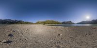 a panorama of a river on a sunny day with clouds in the sky, and rocky ground next to it