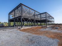 a picture of a building being built on a field near a forest in the background