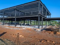 a picture of a building being built on a field near a forest in the background