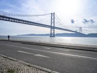 two motorcyclists driving next to the sea under a bridge in spain on a sunny day