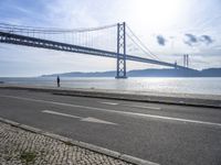 two motorcyclists driving next to the sea under a bridge in spain on a sunny day