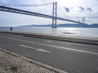 two motorcyclists driving next to the sea under a bridge in spain on a sunny day