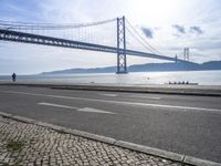 two motorcyclists driving next to the sea under a bridge in spain on a sunny day