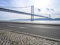 two motorcyclists driving next to the sea under a bridge in spain on a sunny day