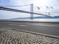 two motorcyclists driving next to the sea under a bridge in spain on a sunny day