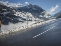 a road on a sunny day with snowy mountains in the background, surrounded by snow and clouds
