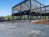 a picture of a building being built on a field near a forest in the background