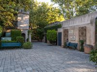 a couple of benches sit outside on a patio and brick walkway that leads to a building