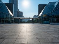 a large, empty courtyard in the middle of some tall buildings with a bright sun shining out