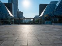 a large, empty courtyard in the middle of some tall buildings with a bright sun shining out