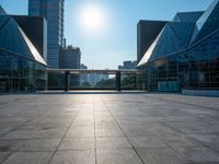 a large, empty courtyard in the middle of some tall buildings with a bright sun shining out