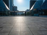 a large, empty courtyard in the middle of some tall buildings with a bright sun shining out