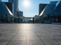 a large, empty courtyard in the middle of some tall buildings with a bright sun shining out