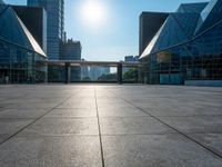 a large, empty courtyard in the middle of some tall buildings with a bright sun shining out