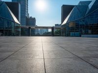 a large, empty courtyard in the middle of some tall buildings with a bright sun shining out