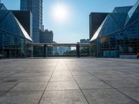 a large, empty courtyard in the middle of some tall buildings with a bright sun shining out