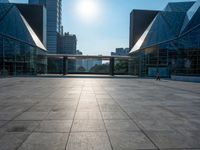 a large, empty courtyard in the middle of some tall buildings with a bright sun shining out