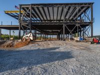 a picture of a building being built on a field near a forest in the background