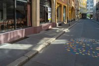 a city street with tables and chairs painted in a colorful tile pattern on the sidewalk