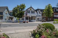 a white building that is in front of some pretty flowers and greenery, and has signs that read country