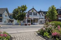 a white building that is in front of some pretty flowers and greenery, and has signs that read country