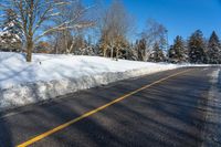 a snow covered road is surrounded by trees and snow - covered mountains in the distance