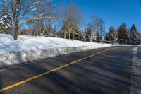 a snow covered road is surrounded by trees and snow - covered mountains in the distance