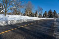 a snow covered road is surrounded by trees and snow - covered mountains in the distance