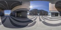 360 lens view of empty plaza with people walking nearby and buildings in the background and sun glaring over