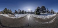 a view of two road through a fish eye lens lens, with snow covered ground and trees in the background