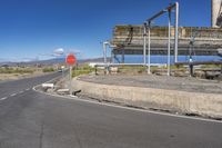 a stop sign in front of a concrete building on a side walk with mountains in the background