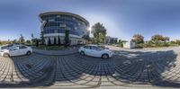 a spherical view of a parking lot with cars in front of a building and another car on the street