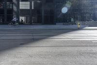 a man riding a bike past buildings on the side of the road in front of a fire hydrant