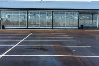 a parking lot with many parking spaces and a large building behind it, and some large windows