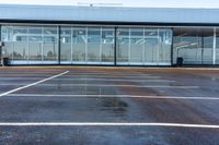 a parking lot with many parking spaces and a large building behind it, and some large windows