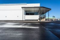 an empty parking lot with no people inside it and a man walking to the building