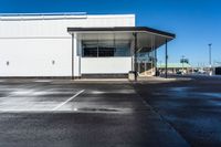 an empty parking lot with no people inside it and a man walking to the building